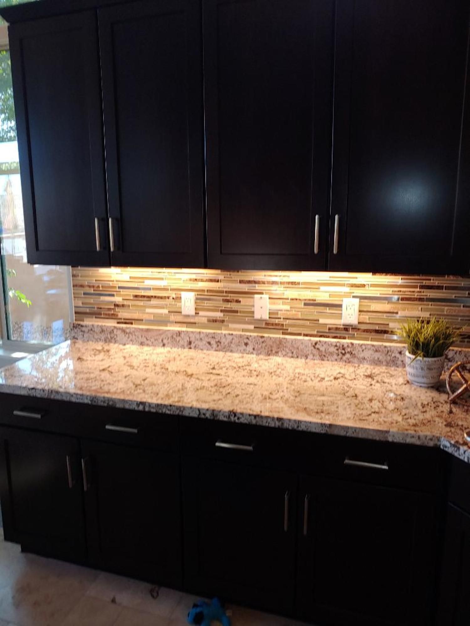 A kitchen with black cabinets and granite counter tops