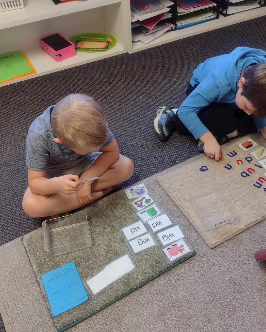 Gymnast in red leotard and white pants, on parallel bars, legs extended, in a gymnasium.