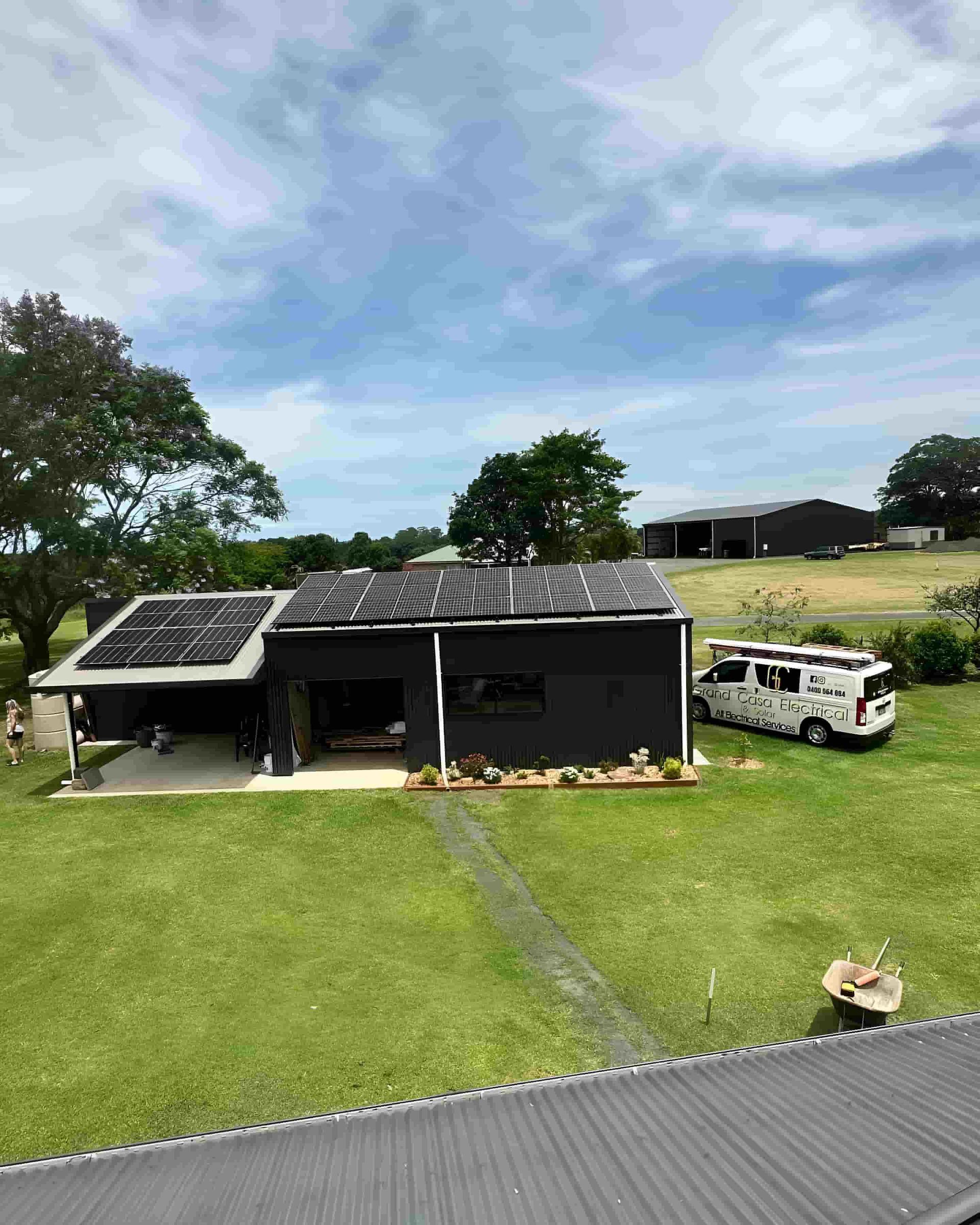 A House With Solar Panels On The Roof And A Van Parked In Front Of It — Grand Casa Electrical Solar & Batteries In Alstonville, NSW