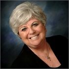 A woman in a black jacket and necklace is smiling for the camera.