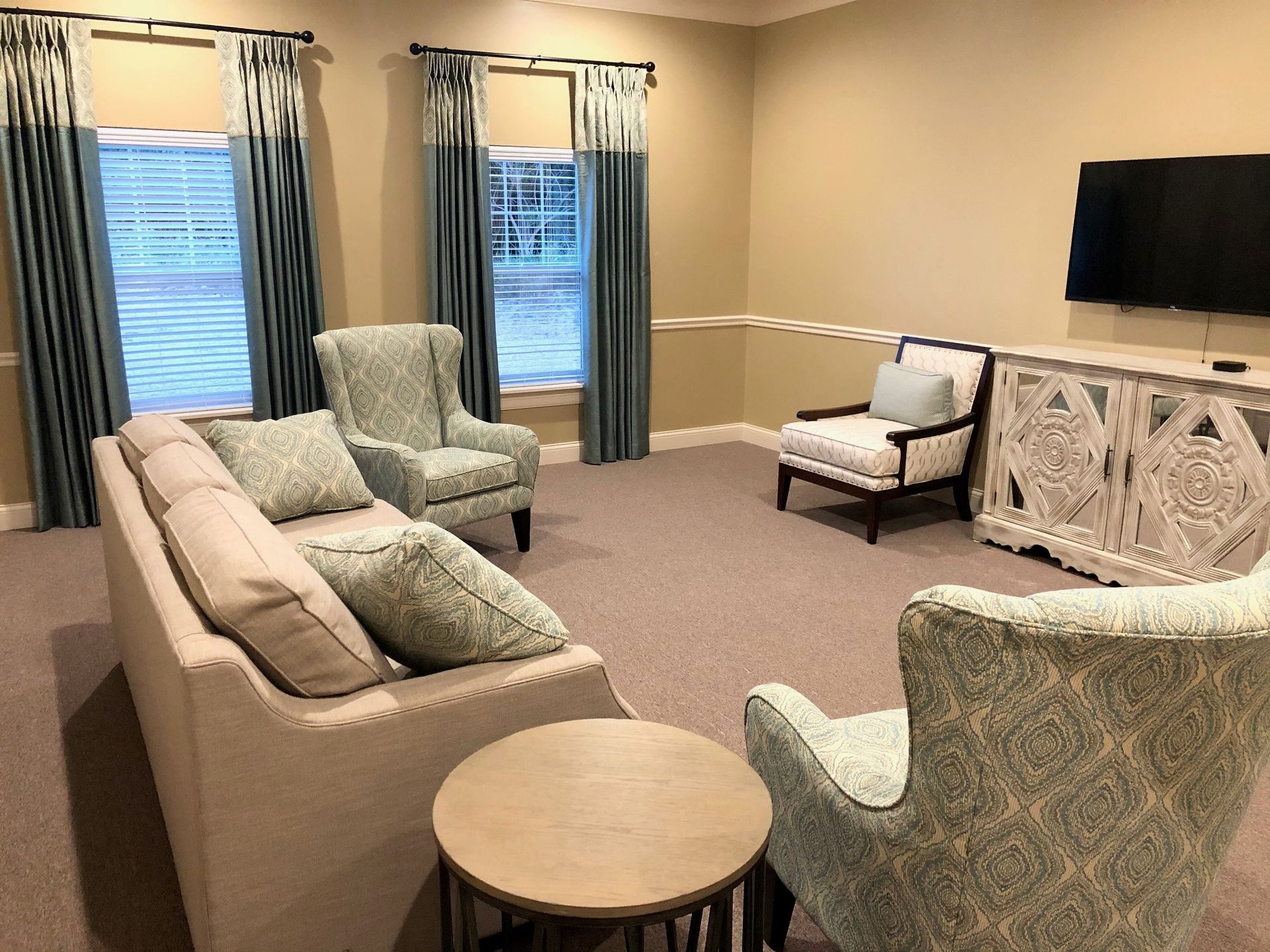 A living room with a couch , chairs , tables and a flat screen tv.