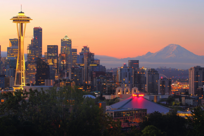 A city skyline with a mountain in the background at sunset