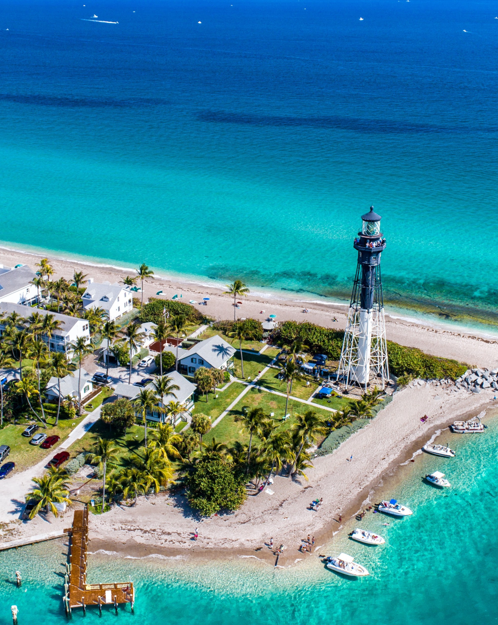 An aerial view of a lighthouse on a small island in the middle of the ocean.