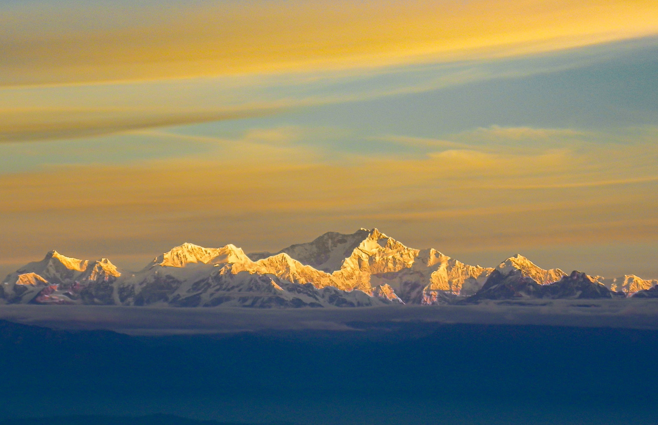 A view of a snowy mountain range at sunset.