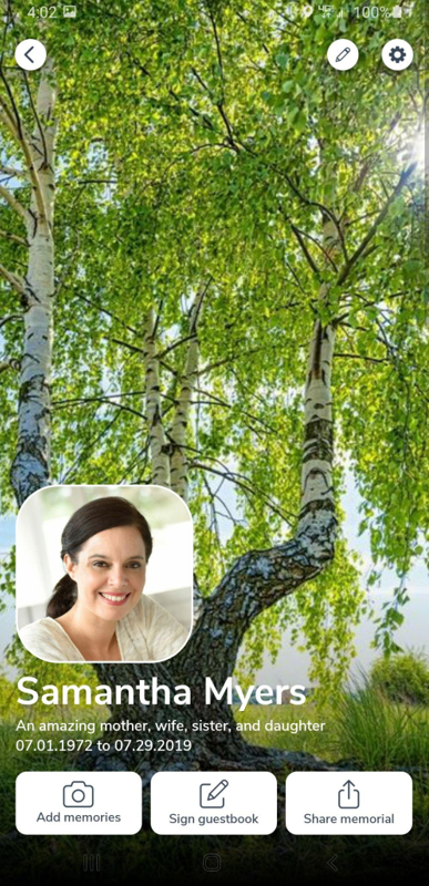 A woman is smiling in front of a tree on a phone screen.