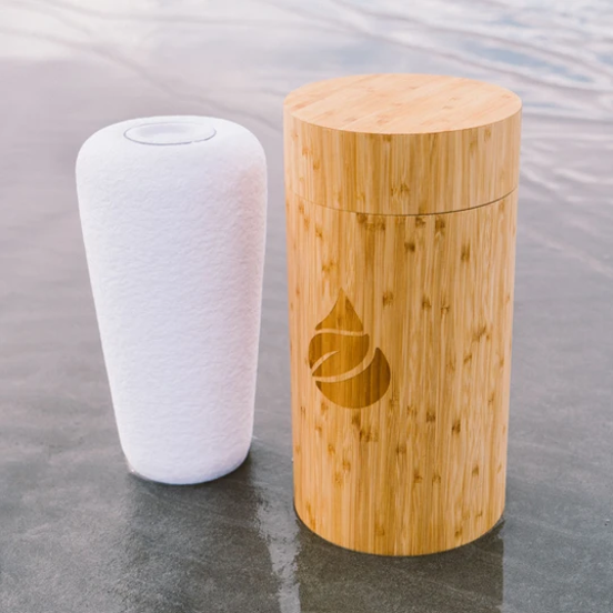 A white vase next to a wooden container with a drop on it