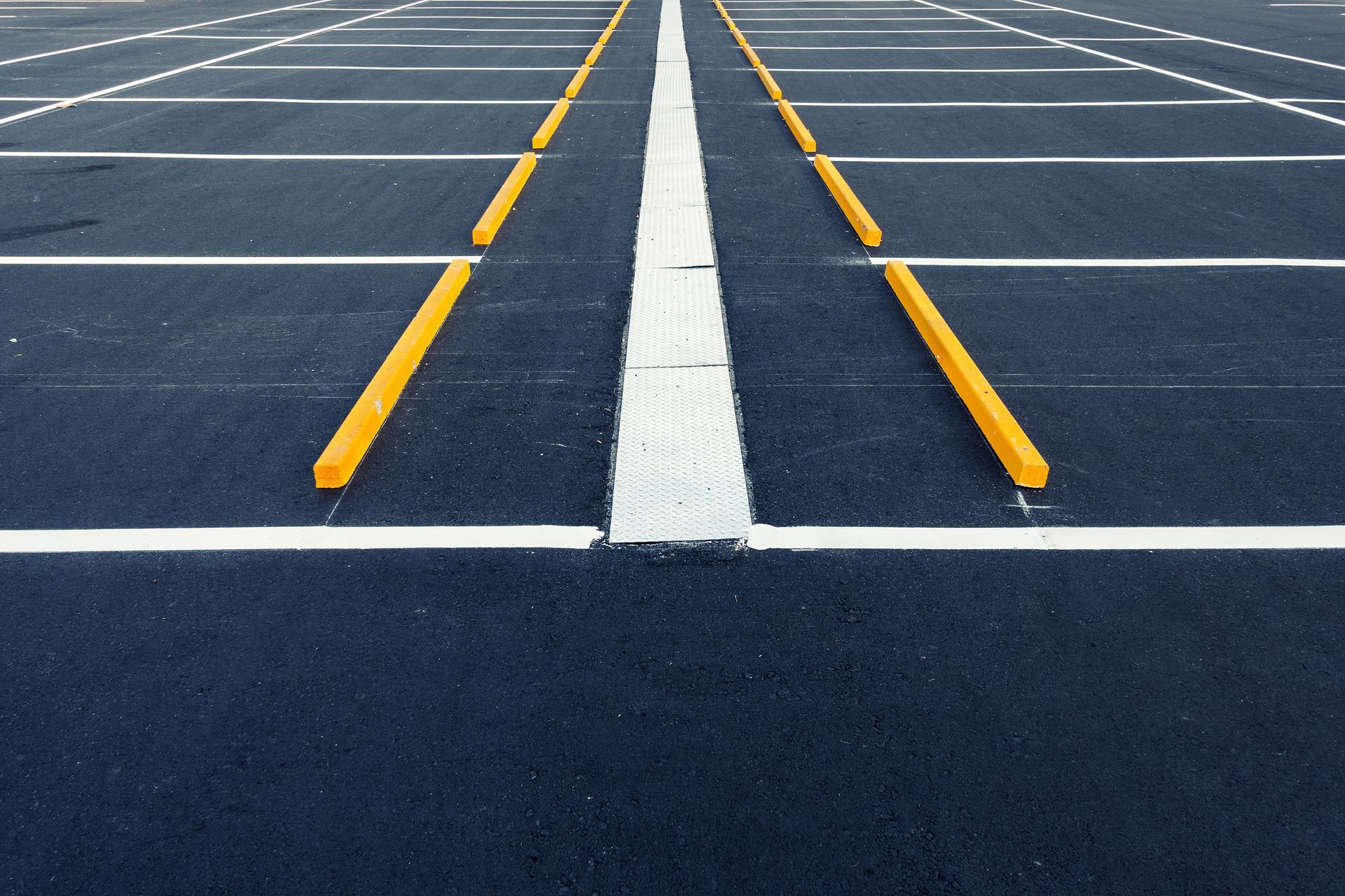 Empty parking lot with white and yellow painted lines on dark asphalt