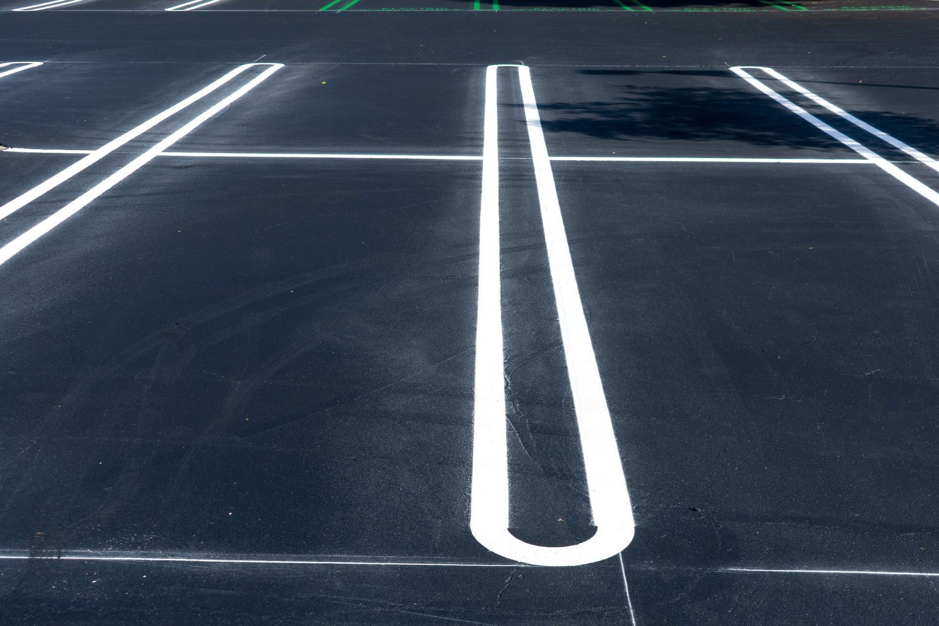 Empty parking lot with white painted stall lines on dark asphalt