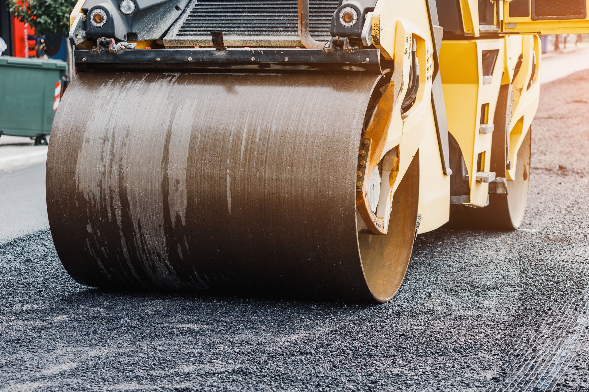 Yellow road roller compacting fresh asphalt on a street construction site