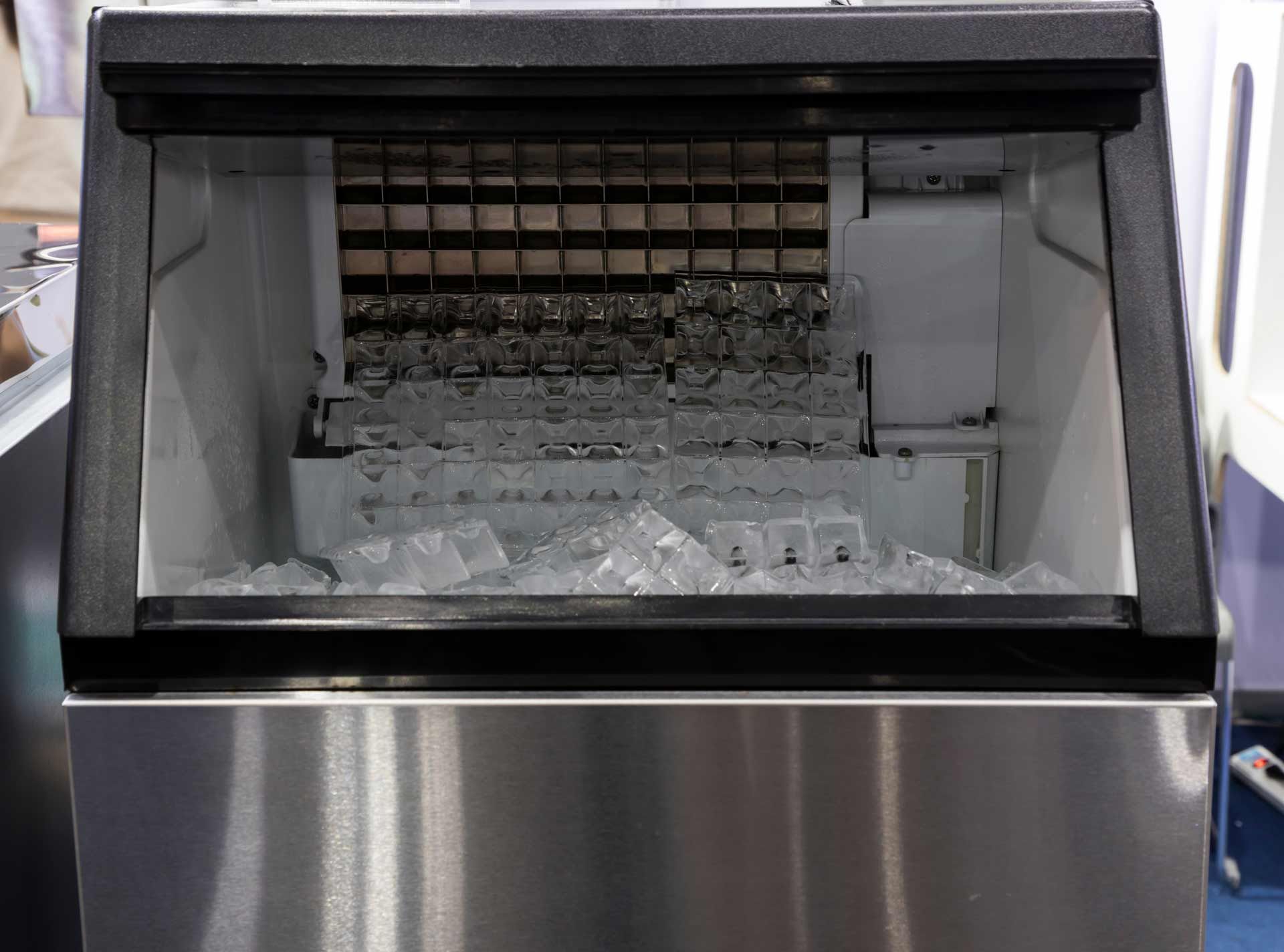 Commercial ice machine, stainless steel exterior, open door showing ice cubes filling the bin.