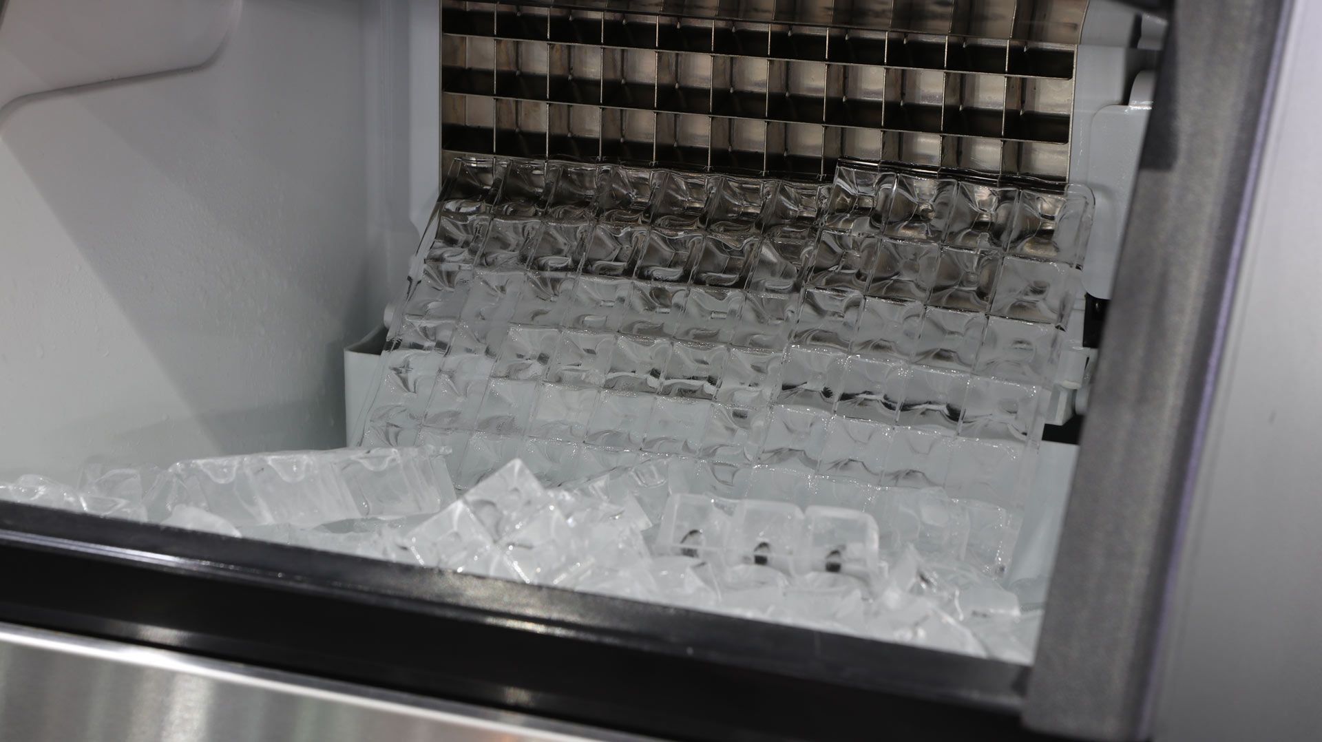 Ice maker interior with formed ice cubes in storage bin.