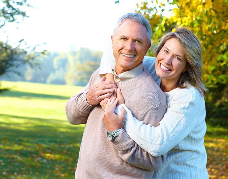 White elderly couple embracing each other at the park