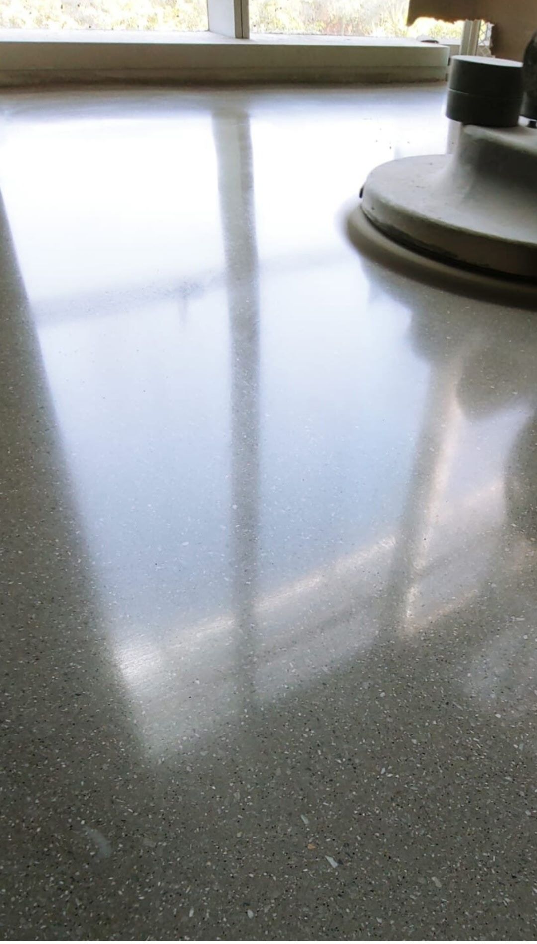 Glossy gray countertop reflecting a window, with a coffee maker base on the right