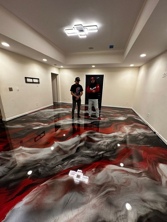 Empty warehouse with a glossy gray epoxy floor and red steel walls and beams.