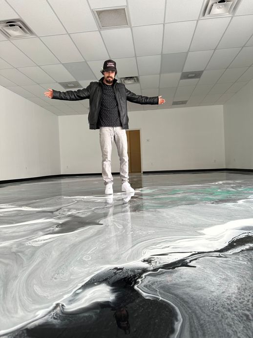 Empty room with glossy black floor and white walls, viewed through a doorway.