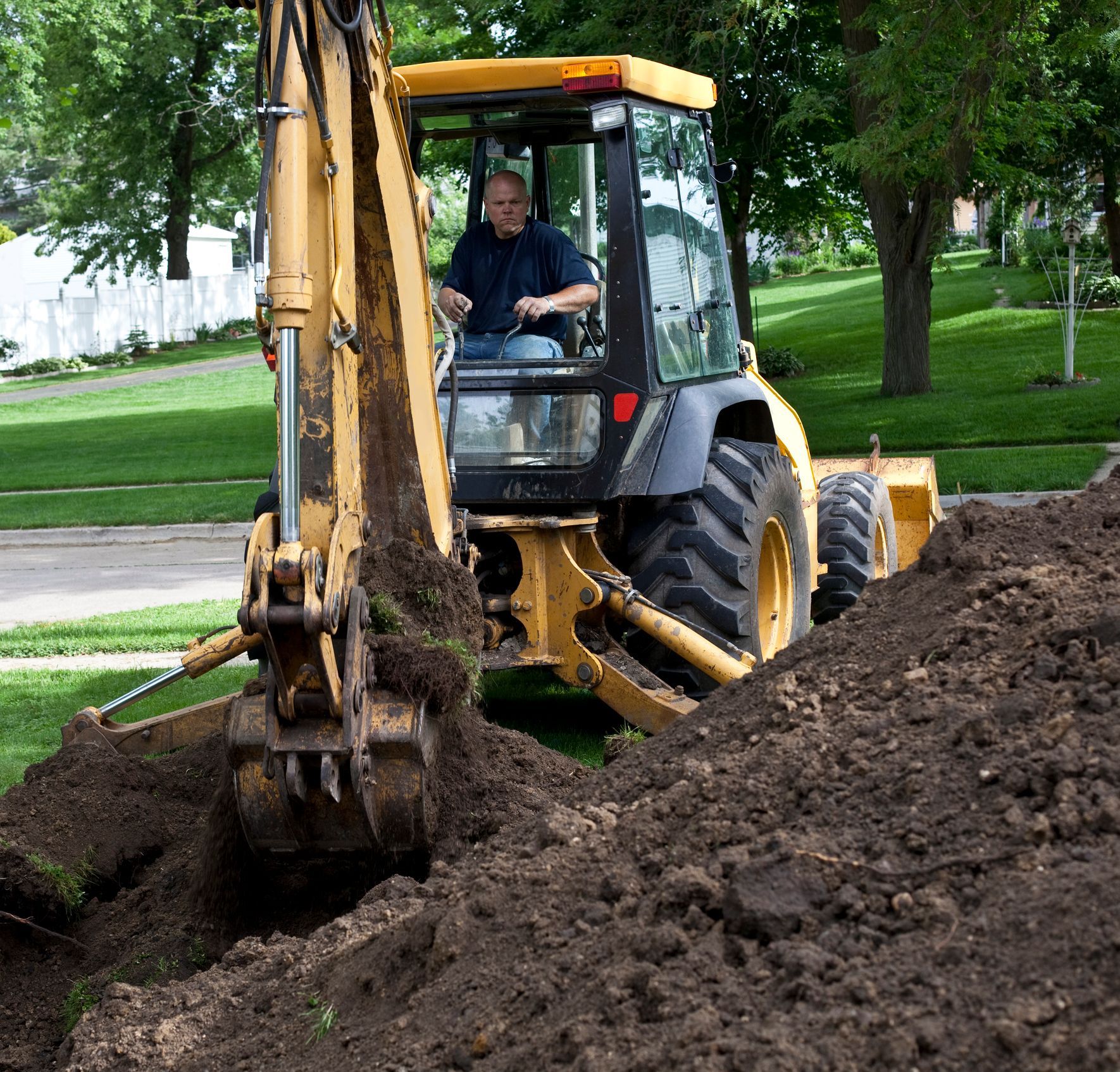 Residential excavation contractor using backhoe in a construction site. Residential excavation contractor using backhoe in a construction site.
