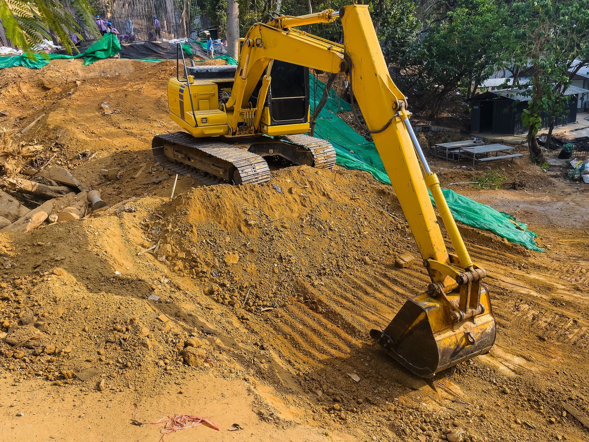 A yellow excavator on a dirt road operated by residential excavation contractors.