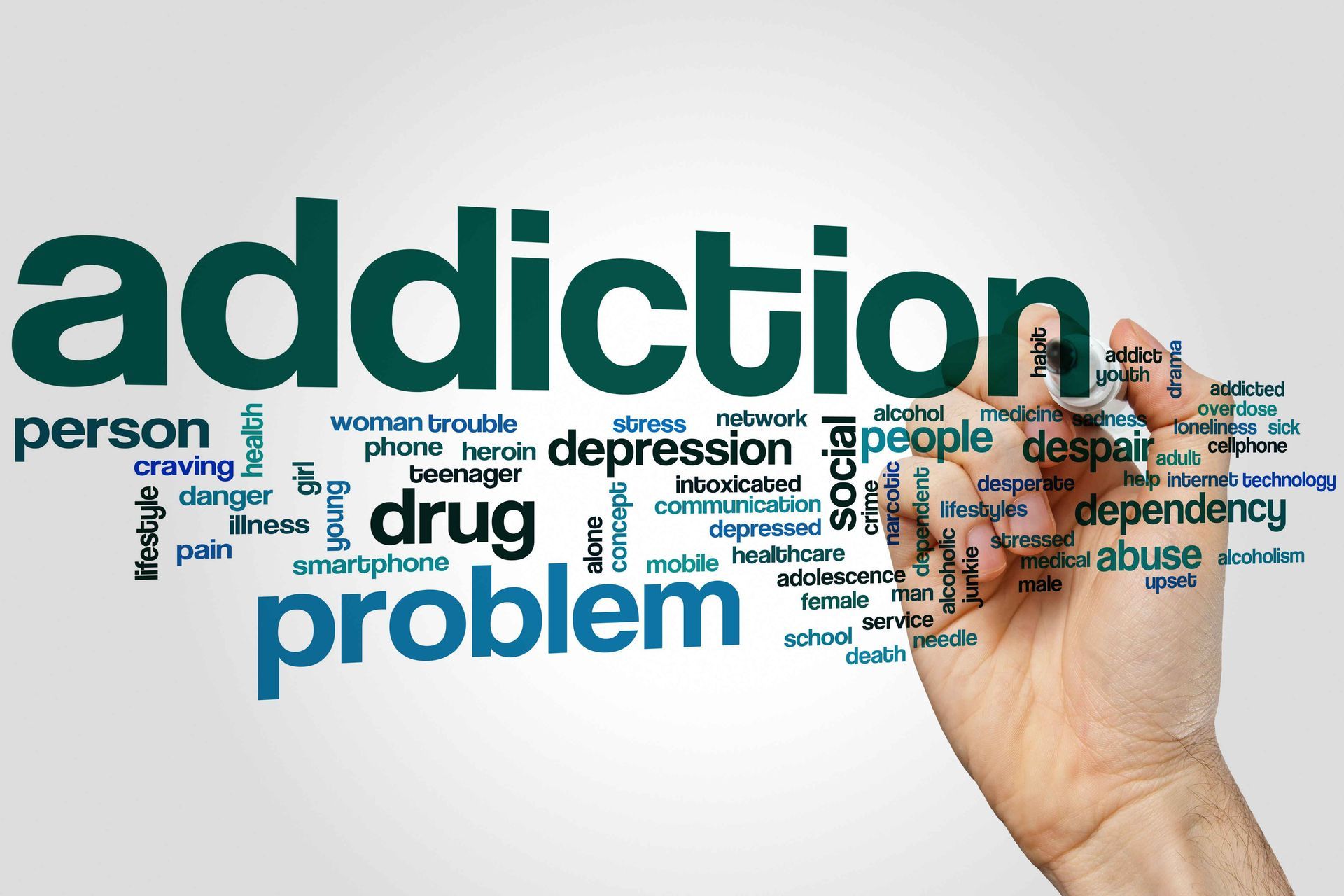 a hand writing out many words associated with addiction
