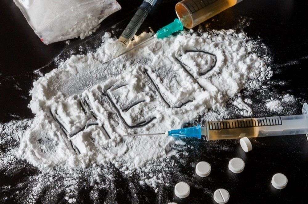 drugs on a table with the word help written in powder