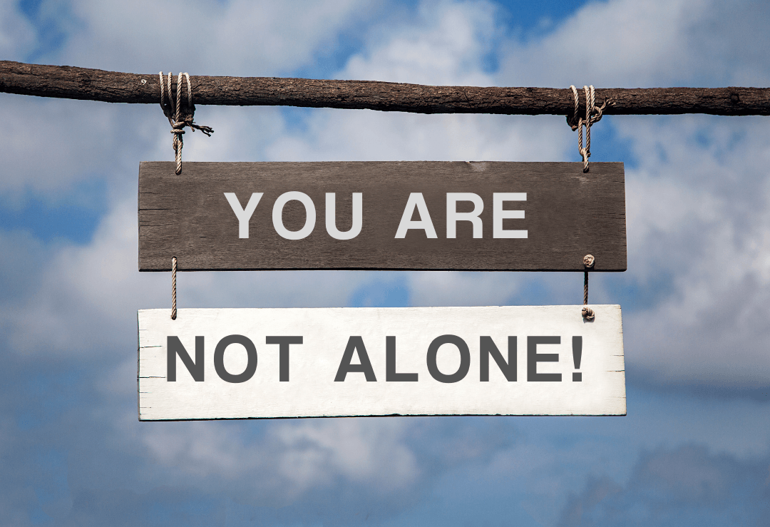 a wooden sign saying you are not alone!