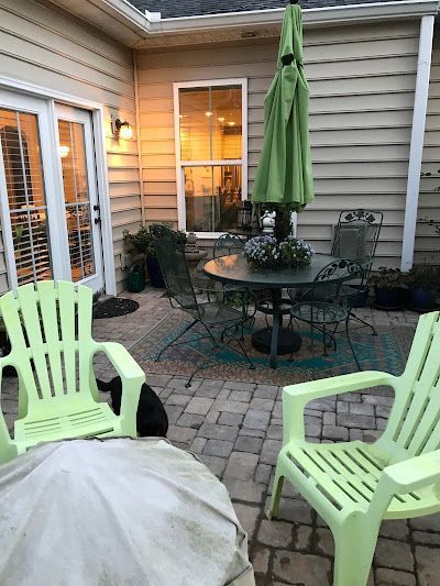 A patio with a table and chairs and a green umbrella.