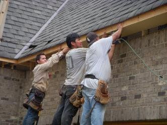 A group of construction workers are working on a roof.