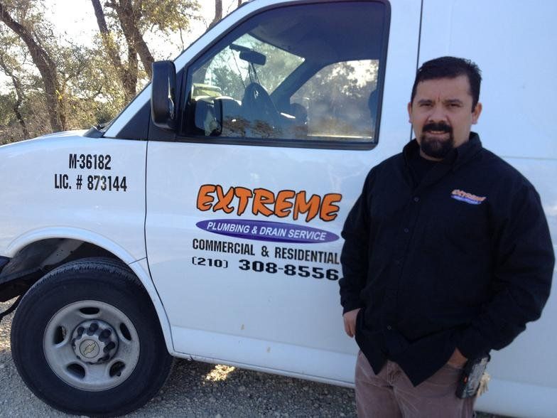 A man stands in front of an extreme plumbing and drain service van