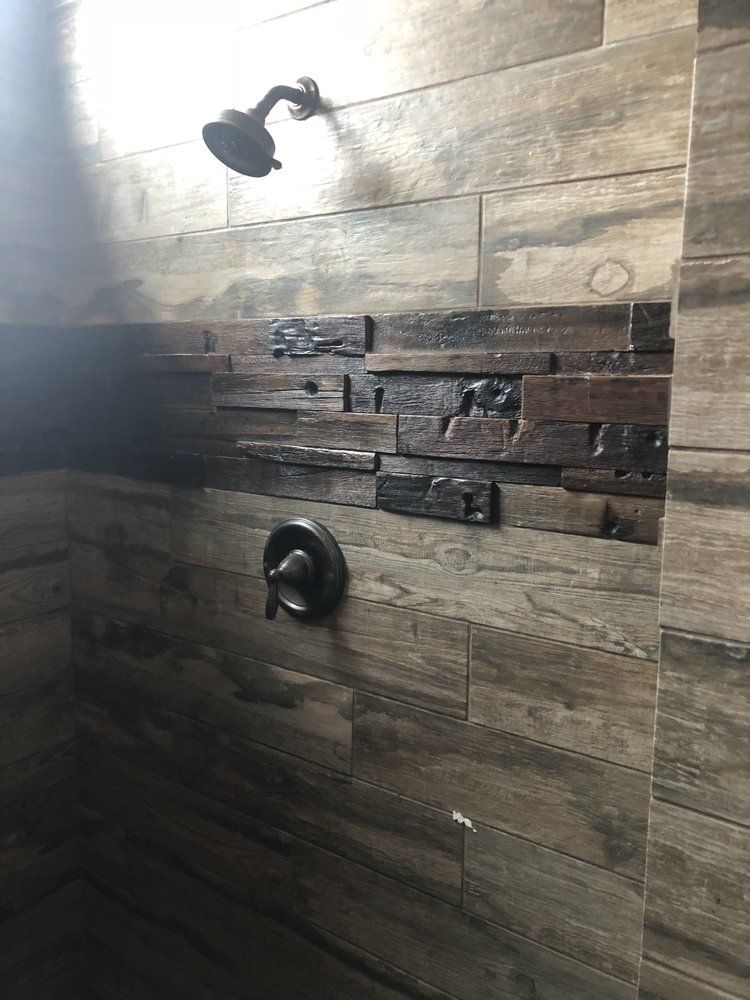 A shower with a wooden wall and a shower head.