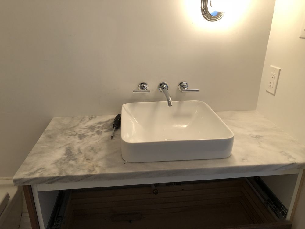 A bathroom sink is sitting on top of a marble counter top.