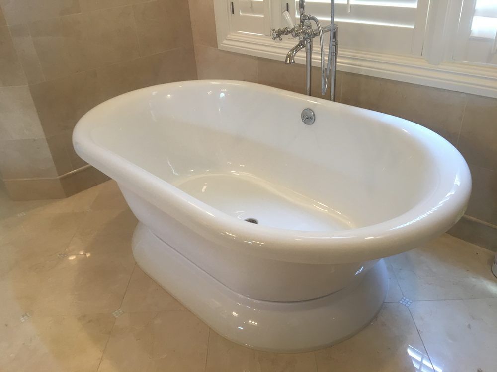 A white bathtub is sitting in a bathroom next to a window.