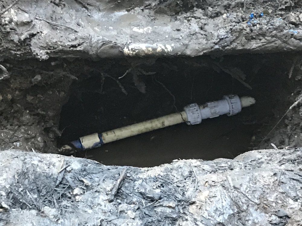 A pipe is laying in the dirt in a hole.