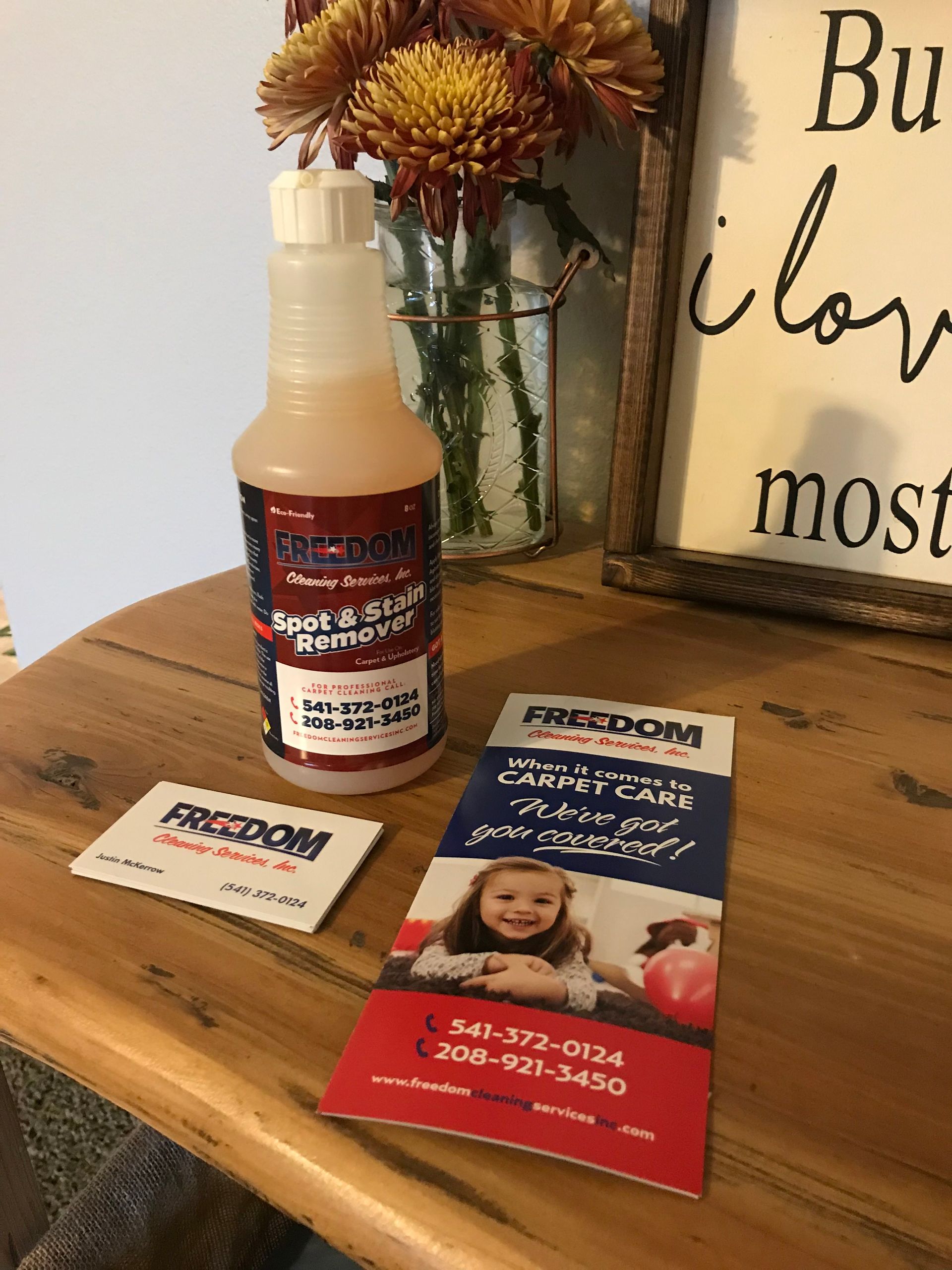 A bottle of freedom is sitting on a wooden table next to a sign.