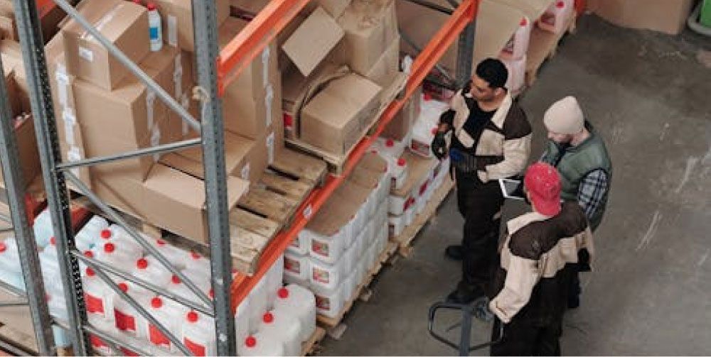 A group of people are standing in a warehouse looking at shelves.