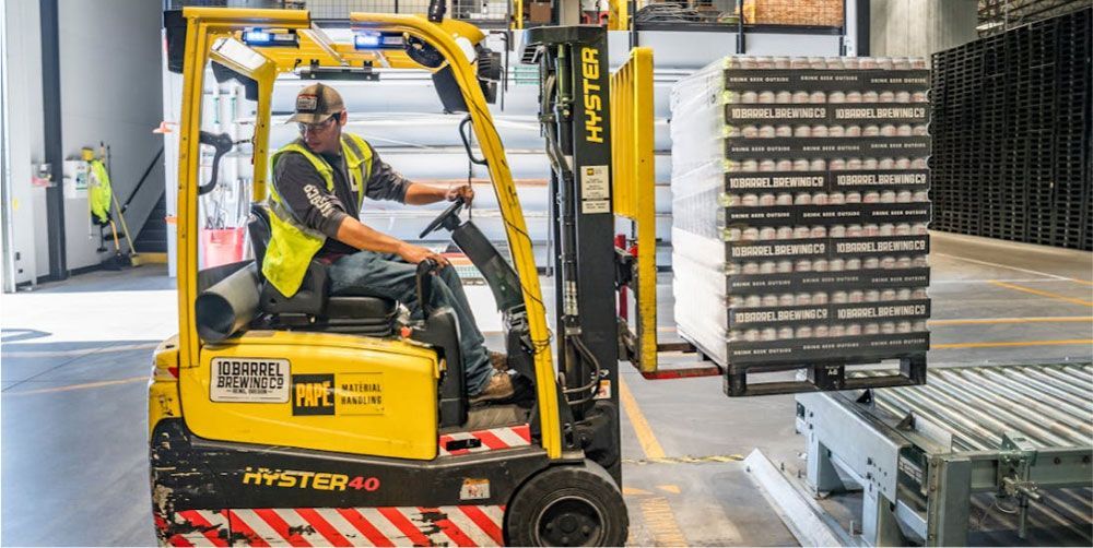 A man is driving a forklift in a warehouse.