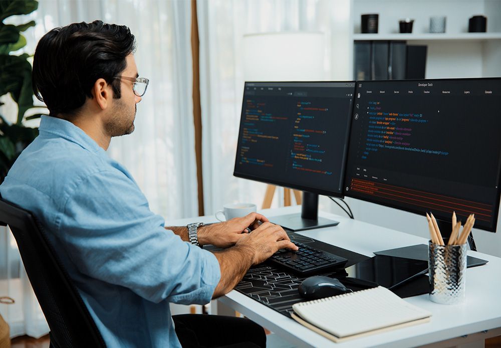 A man is sitting at a desk working on a computer.