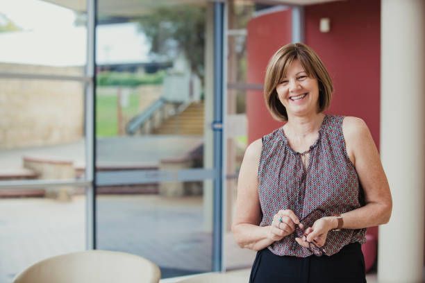 A woman is standing in front of a window smiling.