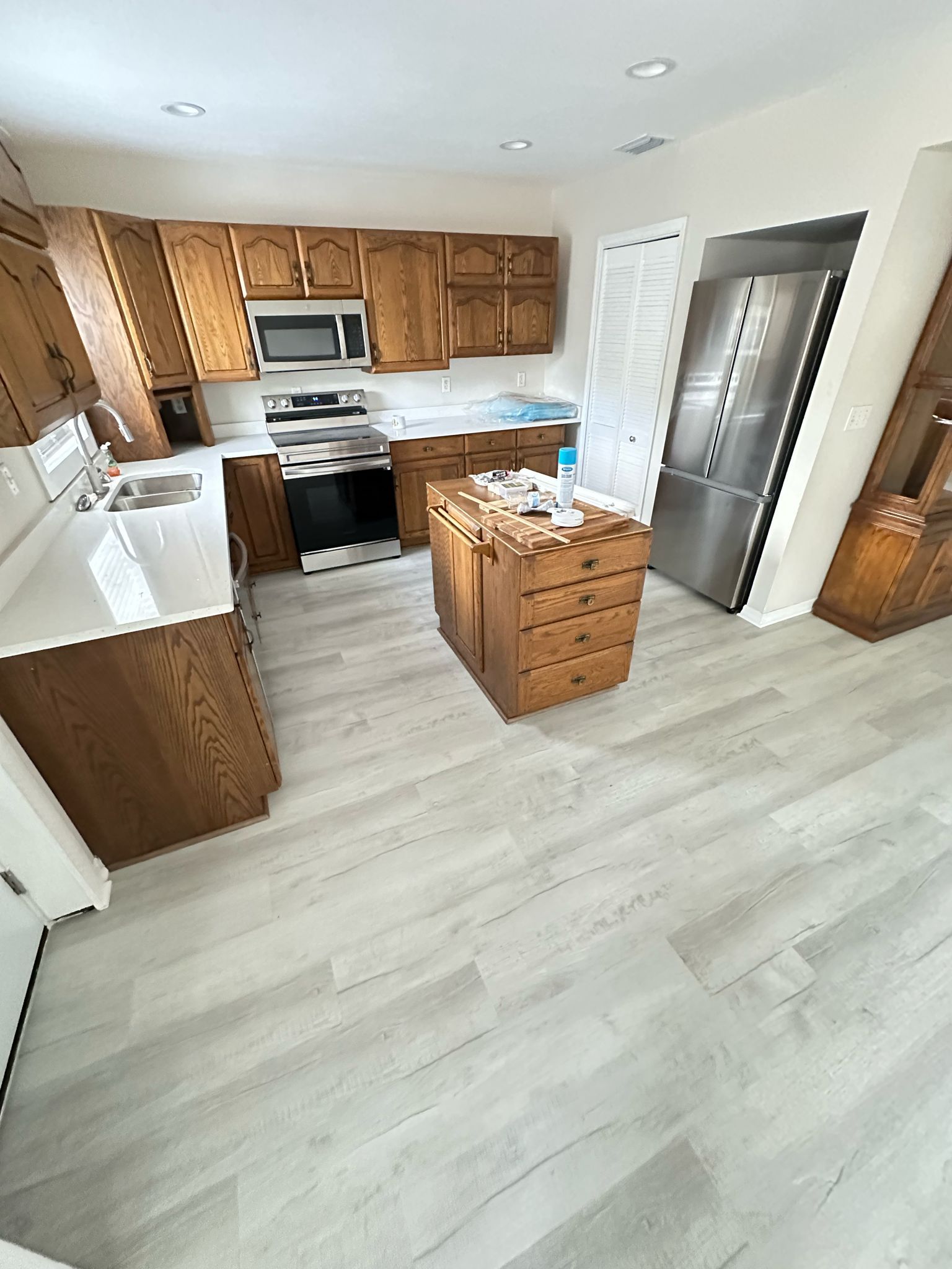 Kitchen with wooden cabinets, white countertops, stainless steel appliances, and light gray flooring.