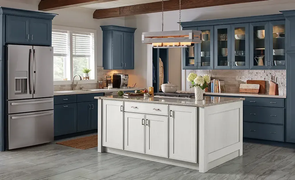 Blue and white kitchen with island, stainless steel refrigerator, and glass-front cabinets.