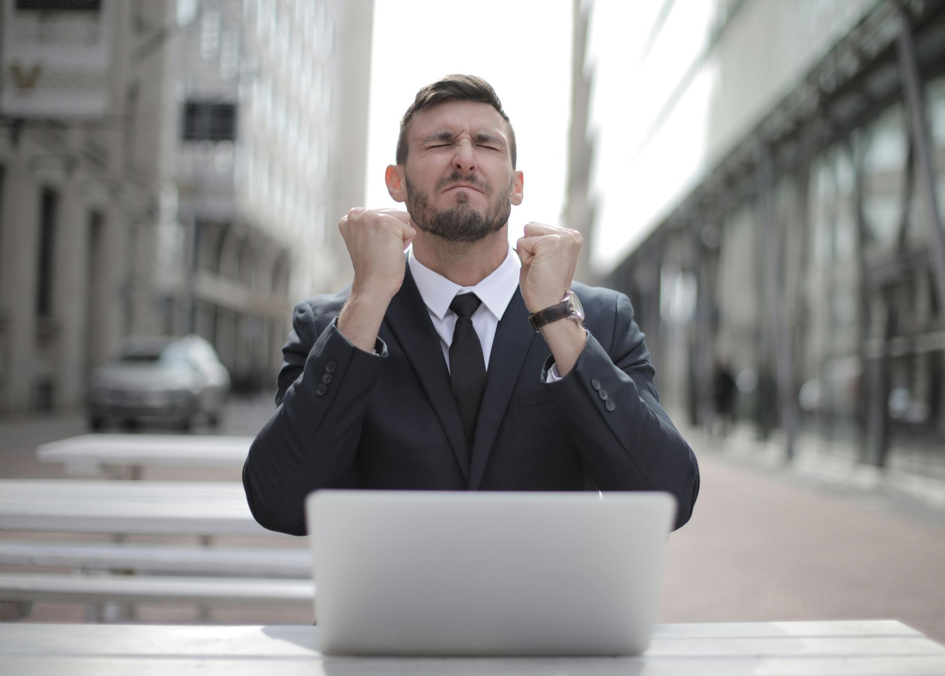 A man in a suit and tie is sitting in front of a laptop computer.