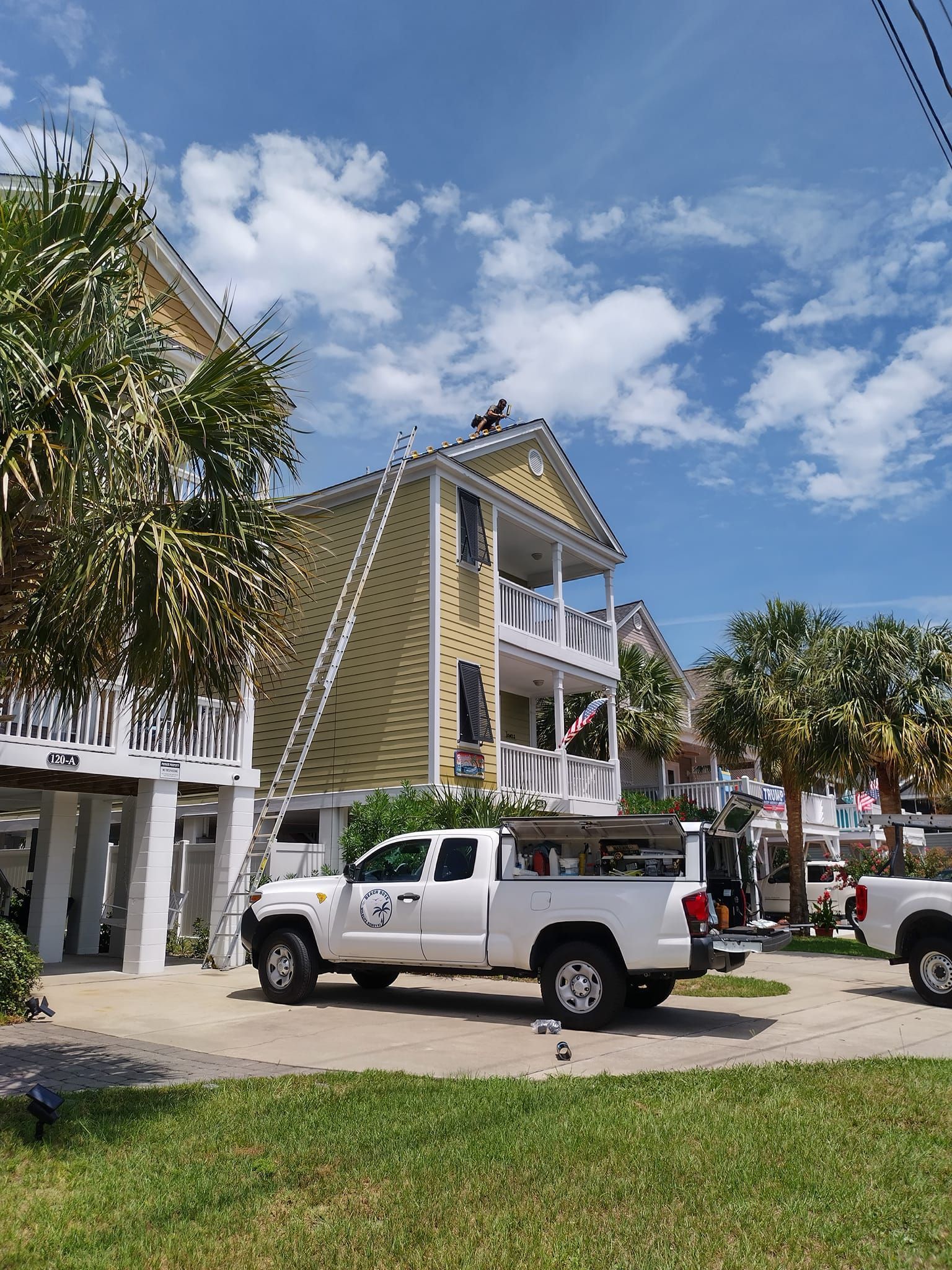 A white truck is parked in front of a yellow house.