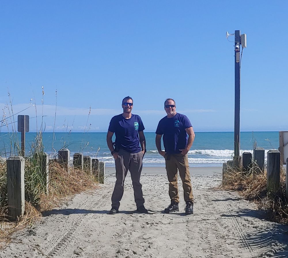 Two men standing next to each other on a beach