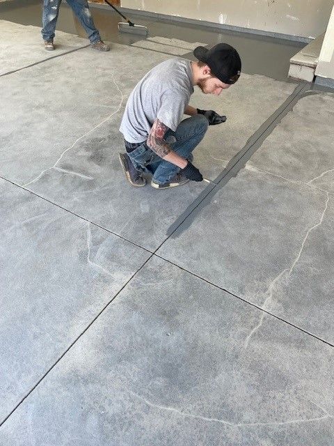 A man is kneeling down on a concrete floor.