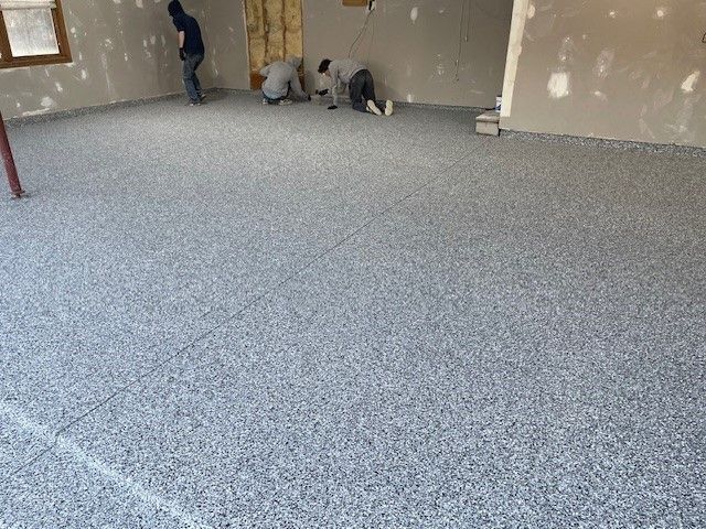 A group of people are working on a concrete floor in a room.