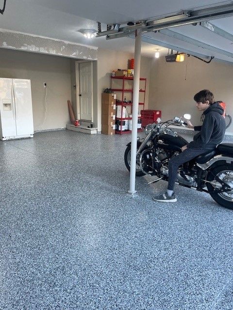 A man is sitting on a motorcycle in a garage.