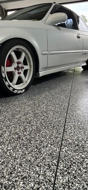 A silver car is parked in a garage with a gray floor.