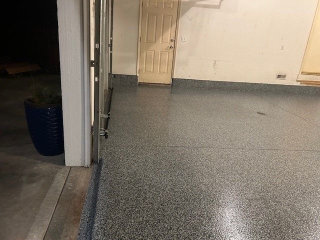 A garage with a gray floor and a white door.