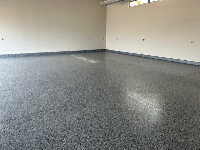 A large empty garage with a gray floor and white walls.