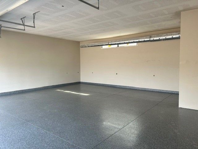An empty garage with a gray floor and white walls