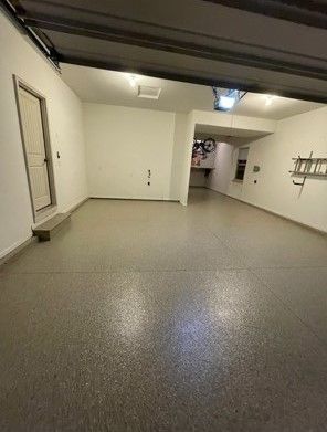 A garage with a garage door open and a gray floor.