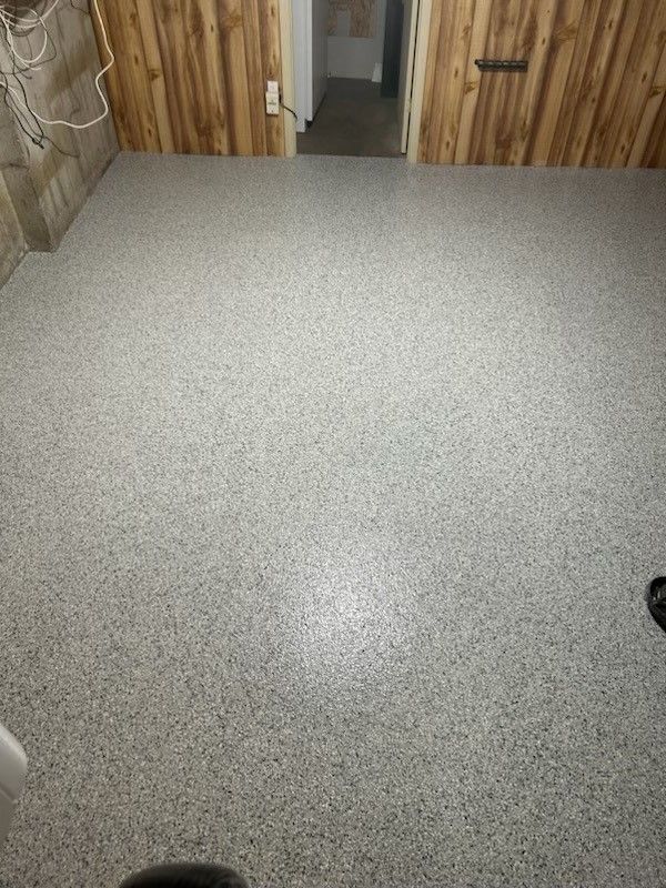 A room with a gray floor and wooden walls.